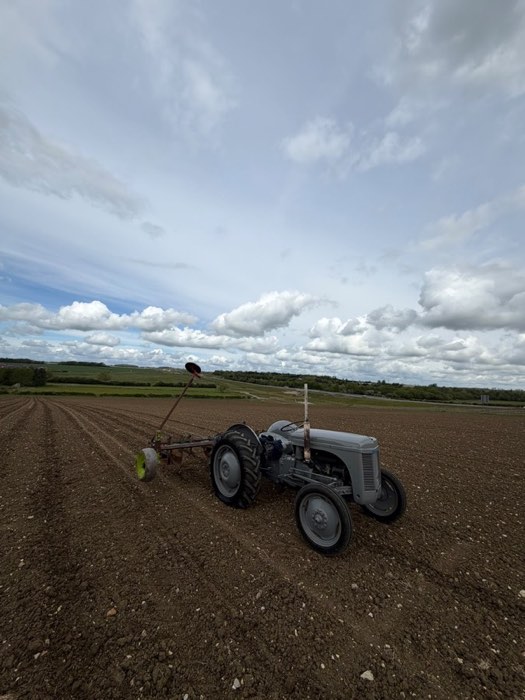 A vintage grey tractor parked in the field under a big sky