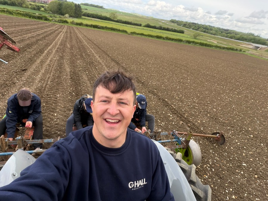 Sowing pumpkin seeds from the back of a trailer in a freshly drilled field